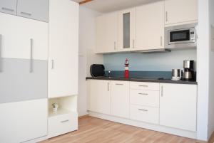 a white kitchen with white cabinets at Hanseatic 204 in Duhnen