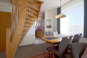 a dining room with a table and a wooden staircase at KD2-07 Schiffsjunge in Dorum-Neufeld