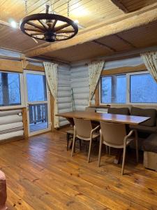 a dining room with a table and chairs and windows at Domik v gorakh in Bukovets