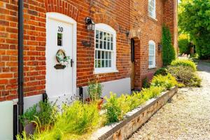 a brick house with a white door and some plants at Thyme Cottage in Beccles