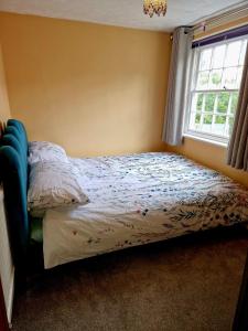 a bed in a bedroom with a window at Thyme Cottage in Beccles