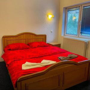 a bed with red sheets and two pairs of shoes on it at Hotel Gryka in Peje