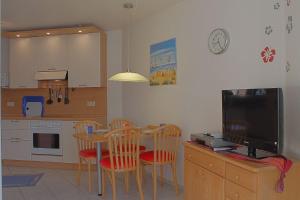 a kitchen with a table and chairs and a television at LT 33a Bungalow Max in Dorum-Neufeld