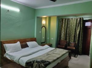 a bedroom with a large bed and a chair at Hotel Hari mangalam heritage in Tehri-Garhwāl
