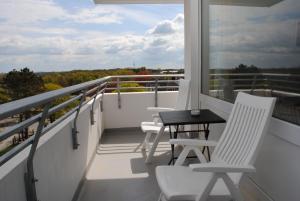 a balcony with white chairs and a table on it at Hanseatic 512 in Duhnen
