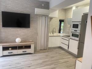 a kitchen with white cabinets and a flat screen tv on a wall at Casita Mona Marcoin in Toledo
