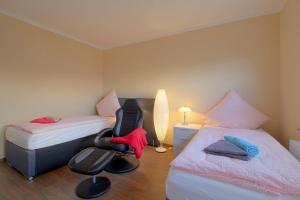a bedroom with two beds and a chair in a room at Gästehaus Dorum 03 in Dorum