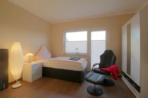 a bedroom with a bed and a chair and a window at Gästehaus Dorum 03 in Dorum