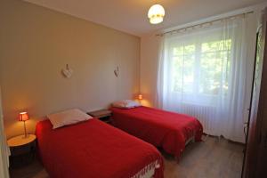 two red beds in a room with a window at La fontaine in Saint-Mathieu