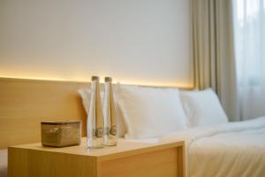 a hotel room with a bed and a night stand with four bottles at Koji House in Jakarta