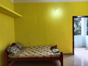 a bed in a room with a yellow wall at Nandy Delight Homestay in Kanyakumari