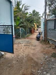 a motorcycle parked on a dirt road next to a building at Nandy Delight Homestay in Kanyakumari +6 photos