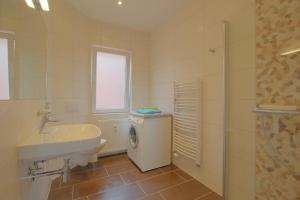 a bathroom with a sink and a washing machine at Gästehaus Dorum 01 in Dorum