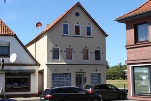 a white house with two cars parked in front of it at Gästehaus Dorum 01 in Dorum +1 photo