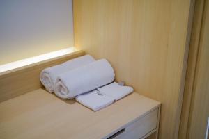 two towels sitting on a shelf in a room at Koji House in Jakarta