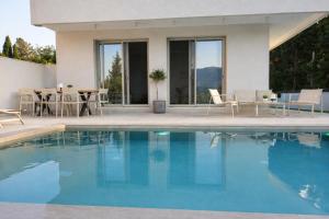 a house with a swimming pool and a table and chairs at Villa Harmony Luxury Resort in Corfu