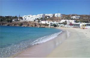 a beach with a group of white buildings and the ocean at Mykonos Beachfront House with Sunset & Delos View in Agios Stefanos