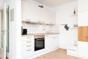 a white kitchen with white cabinets and appliances at Hanseatic 111 in Duhnen