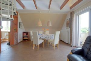 a dining room with a table and white chairs at KA8 Beim Wattn Fischer in Wremen