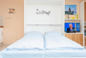a white bed in a room with a tv at Hanseatic 210 in Duhnen
