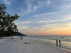 a group of people on the beach at sunset at Para Hostel Kohrong in Kaôh Rŭng (3)