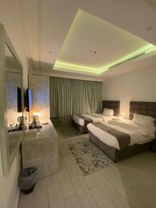 a hotel room with two beds and a television at Gardenia Park Quraish hotelفندق جاردينا بارك قريش in Jeddah