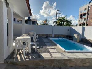 a patio with a table and chairs and a swimming pool at Casa em Praia Formosa in Cabedelo