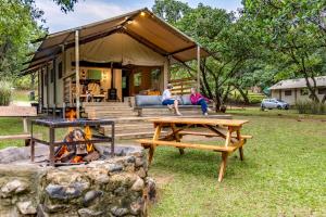 two people sitting on the porch of a tent with a fire pit at AfriCamps at Mackers 