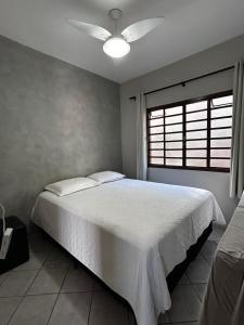 a bedroom with a white bed with a ceiling fan at Mirante do Lago in Capitólio +87 photos