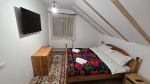 a bedroom with a bed and a tv on the wall at La Murmur de Padure in Bălnaca