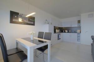 a white kitchen with a white table and chairs at Apartment 256 in Hohegeiß