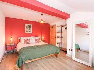 a bedroom with a red wall with a bed at Joy's Cottage in King's Lynn