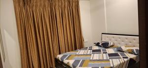 a bedroom with a bed with a blanket and curtains at Soni & Avi View Apartment in Igatpuri