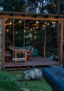 a wooden pergola with a table and chairs on a deck at Casa Picătura de Rouă in Beliş