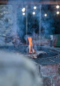 a grill with meat and a fire in it at Casa Picătura de Rouă in Beliş