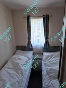two beds in a bedroom with words written on the wall at Caravan 127 in Barmouth