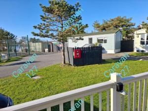 a yard with a white fence and a house at Caravan 127 in Barmouth