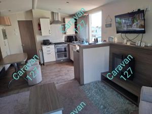a kitchen and living room with a stove and a tv at Caravan 127 in Barmouth +5 photos