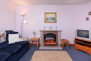 a living room with a couch and a fireplace at Cosy Croft in Lower Shader