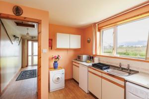 a kitchen with a sink and a washing machine at Cosy Croft in Lower Shader