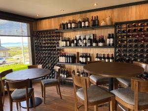two tables and chairs in a room with wine bottles at Ayres de Calafate in El Calafate