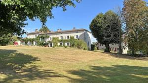 a large white house on a grassy field at Domaine de gensignac in Séreilhac