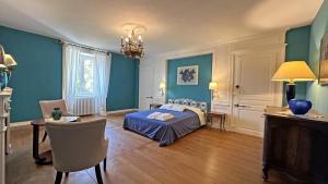 a bedroom with blue walls and a bed and a table at Domaine de gensignac in Séreilhac +49 photos