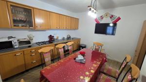 a kitchen with a red table and chairs and a kitchen with a table at La Murmur de Padure in Bălnaca +16 photos