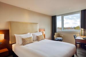 a hotel room with a bed and a desk and a window at Thistle London Hyde Park Kensington Gardens in London
