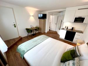 a bedroom with a large white bed and a kitchen at Apart-Hôtel Pont-de-Thielle in Gals
