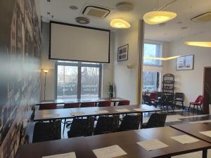 a conference room with tables and a large screen at Hotel Zamek Centrum in Szczecin