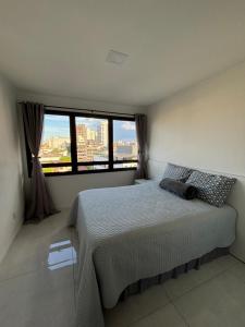 a bedroom with a bed and a large window at Loft moderno e completo a 200m do Consulado Americano in Porto Alegre