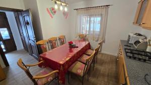 a dining room with a red table and chairs at La Murmur de Padure in Bălnaca