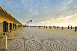 a boardwalk with chairs and umbrellas on the beach at STUDIO 88 in Sainte-Adresse